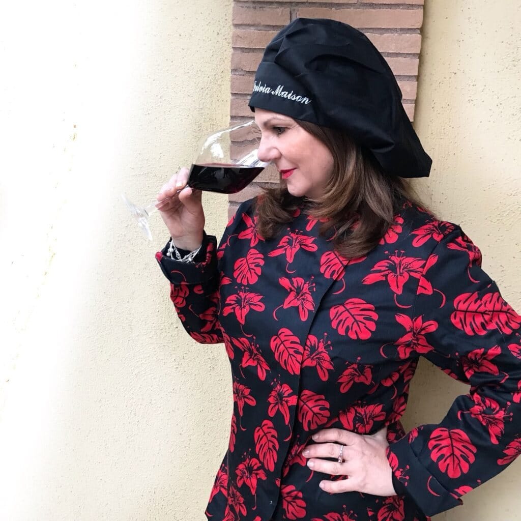 Tiziana Fiorentini in divisa da chef degusta un calice di vino rosso